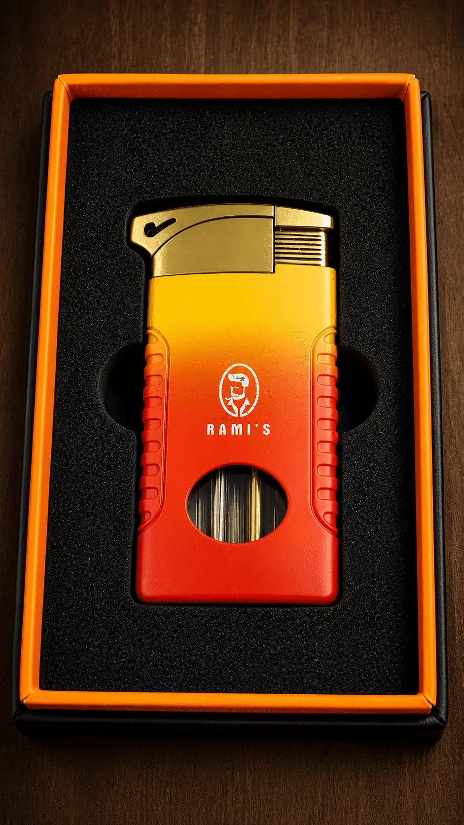A "Rami's" Pipeliner cigar lighter with a bold, sunset-inspired red-to-yellow gradient finish, securely placed inside a black foam-lined display box with a striking orange border.