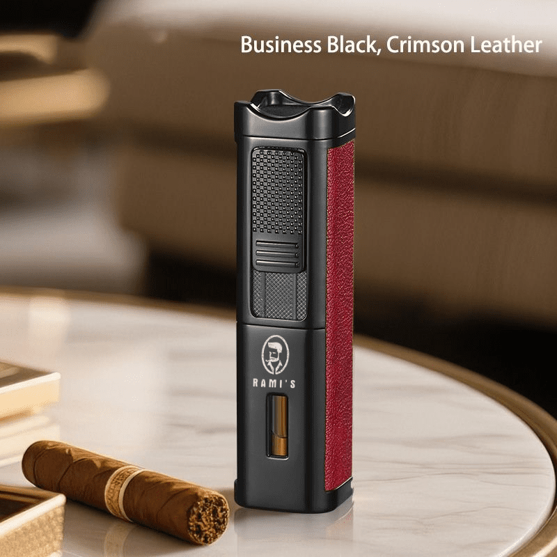 A tall, matte black Rami's Accessories executive lighter with textured crimson leather siding, a fuel window, and the brand logo, standing on a marble table next to a cigar.