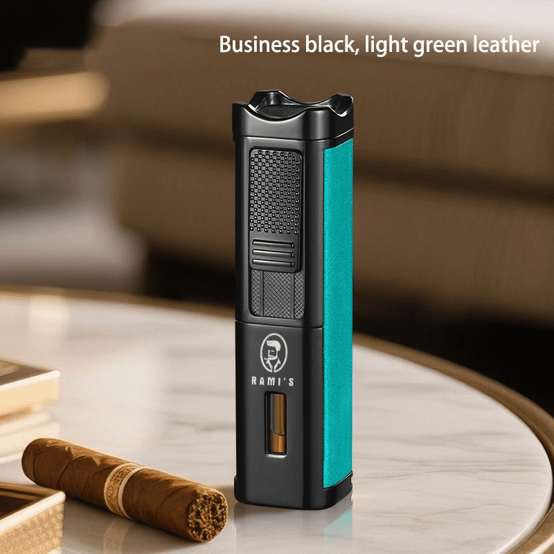 A tall, matte black Rami's Accessories executive lighter with textured light green leather siding, featuring a fuel window and the brand logo, standing on a marble table next to a cigar.