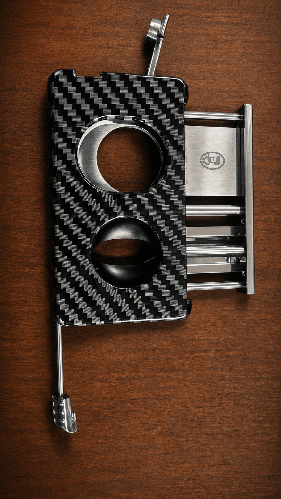 Rami's Carbon Elite Cutter luxury carbon fiber 4-in-1 cigar cutter featuring a guillotine cutter, V-cutter, cigar punch, and draw poker displayed on a wooden surface.