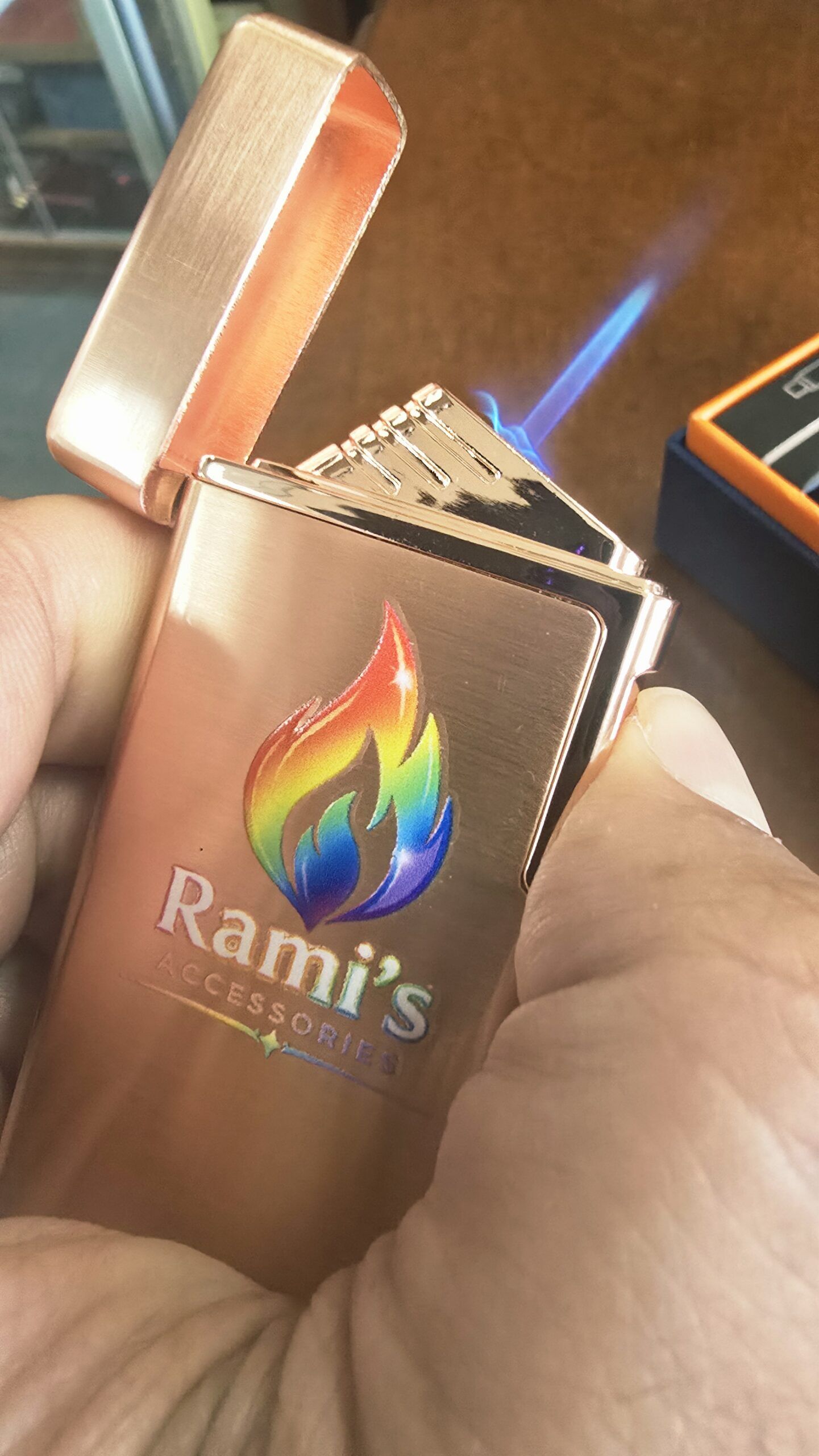 Rose gold Rami's Prizm dual-flame lighter held in hand, demonstrating the intense blue torch flame ignition.