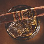 A lit Oliva Serie V Melanio cigar placed on a glass of cognac, highlighting a perfect blend of sophistication