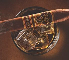 A lit Oliva Serie V Melanio cigar placed on a glass of cognac, highlighting a perfect blend of sophistication