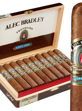 Single Alec Bradley Prensado Lost Art cigar with dark wrapper in front of an open box showing multiple cigars inside.