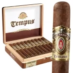 Single Alec Bradley Tempus cigar with dark wrapper, resting in front of an open box showing multiple cigars inside.