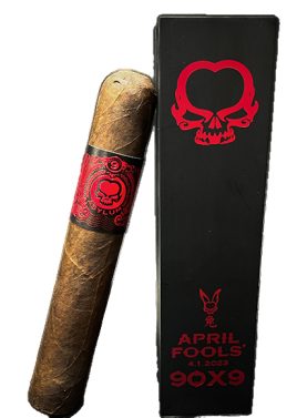 Asylum April Fools cigar resting beside its branded wooden coffin box on a wood surface