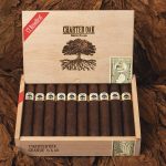 Open box of Charter Oak Maduro cigars resting on rich tobacco leaves, showcasing dark, oily wrappers and expert craftsmanship