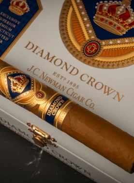 Diamond Crown Classic cigar resting on a closed wooden box with elegant gold and red branding.