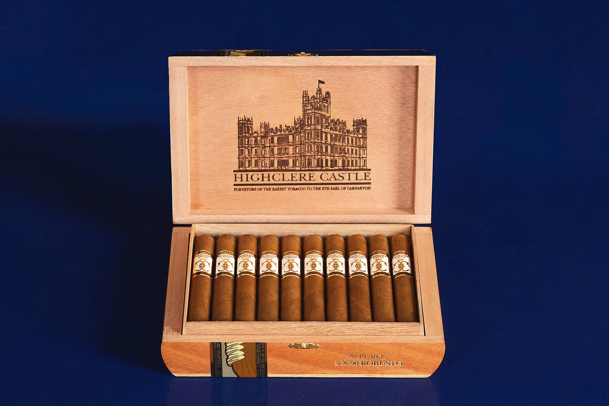 Open box of Highclere Castle cigars, featuring golden-brown wrappers neatly arranged inside an elegant, crest-embossed box
