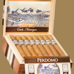 "An open box of Perdomo Lot 23 Connecticut cigars, showcasing the light, smooth wrappers and distinct Padron bands, neatly arranged inside a premium wooden box.