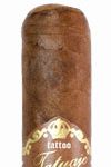 Single Tatuaje 10th Anniversary cigar with a dark, oily wrapper and signature band, resting on a wooden surface.