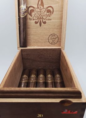 This image features a single Tatuaje 10th Anniversary cigar placed on a polished wooden surface. The cigar showcases a rich, dark wrapper with a slightly oily sheen and a box-pressed shape. The cigar’s distinct red-and-black anniversary band stands out, symbolizing the brand’s 10th year of fine craftsmanship. Known for its full-bodied profile and complex flavors, the Tatuaje 10th Anniversary is a must-have for aficionados seeking a rich, Nicaraguan experience.