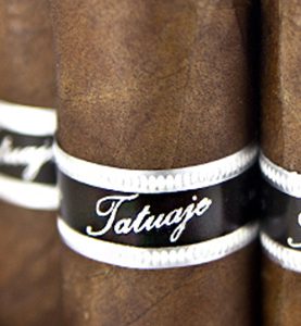 Four loose Tatuaje Black Label cigars with dark, oily sun-grown wrappers arranged side by side
