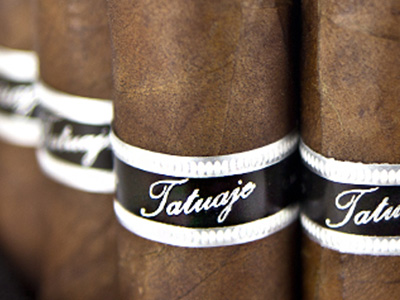 Four loose Tatuaje Black Label cigars with dark, oily sun-grown wrappers arranged side by side
