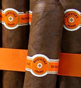 A single Tatuaje Nuevitas cigar resting on a dark wooden surface, showcasing its Corojo ’99 wrapper