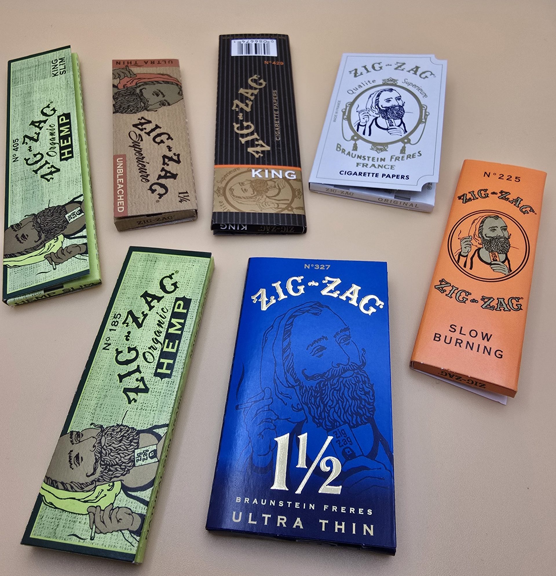 Various styles of Zig Zag Rolling Papers including Classic, Blue, and Organic, displayed with packaging.