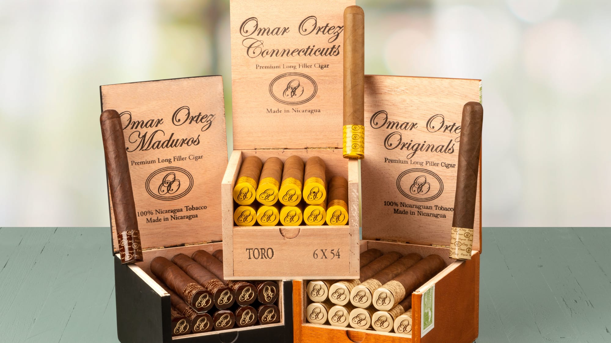 Three open boxes of Omar Ortez cigars showing Connecticut and Maduro wrappers, neatly arranged with visible cigar bands.