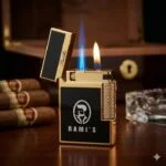 A luxury gold and black Rami's dual-flame lighter featuring a blue torch flame and a soft yellow flame, displayed with premium cigars and a humidor in the background.
