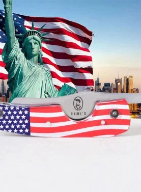 Rami’s American Flag Cigar Knife closed, placed in front of the Statue of Liberty and an American flag, highlighting the patriotic handle and sleek blade