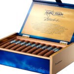 The file aging-room-blue-amber-open-box-jpg displays an open, luxury display box of Aging Room Quattro Nicaragua Blue Amber premium cigars, showcasing a vibrant blue lacquered exterior with gold accents, a metallic gold inner lid with branding script, and neatly arranged cigars with textured blue and silver bands