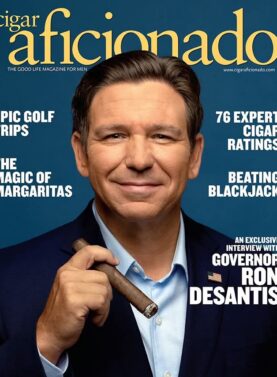 Cover of Cigar Aficionado magazine featuring Florida Governor Ron DeSantis holding a cigar while wearing a navy suit and light blue shirt. Headlines promote golf trips, cigar ratings, margaritas, blackjack tips, and an exclusive interview.