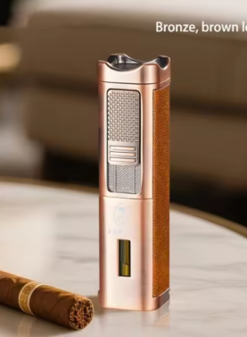 A tall, elegant bronze-finished Rami's Accessories lighter with textured brown leather siding, featuring a fuel window and integrated cigar tools, standing on a marble table next to a premium cigar.