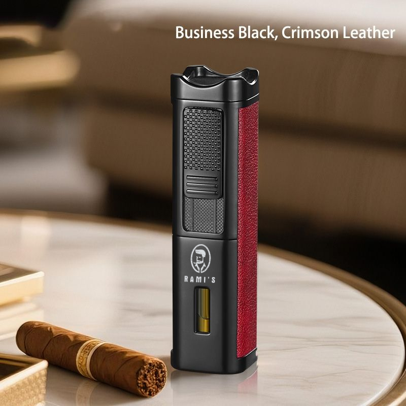 A tall, matte black Rami's Accessories executive lighter with textured crimson leather siding, a fuel window, and the brand logo, standing on a marble table next to a cigar.
