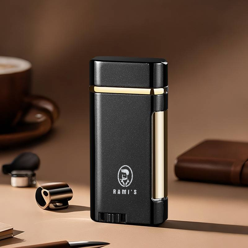 A sleek, matte Onyx Black Rami's Accessories lighter with polished gold accents, standing upright on a desk surface alongside a coffee cup and leather goods.
