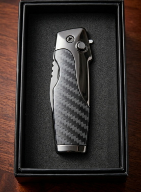A "Rami's" Vanguard cigar lighter featuring a modern carbon fiber body accented with polished gunmetal, including an integrated folding knife and the Rami's mustache-man logo, displayed in a black presentation box.