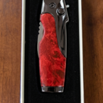 Rami's Vanguard cigar lighter with a black carbon fiber body and polished gold hardware, featuring an integrated side-folding cigar knife with a locking mechanism, in a presentation box.