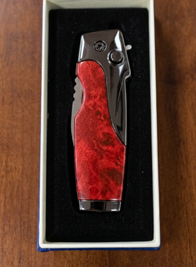 Rami's Vanguard cigar lighter with a black carbon fiber body and polished gold hardware, featuring an integrated side-folding cigar knife with a locking mechanism, in a presentation box.