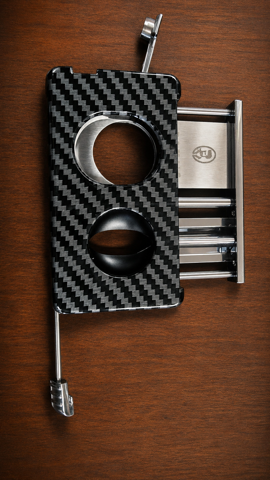 Rami's Carbon Elite Cutter luxury carbon fiber 4-in-1 cigar cutter featuring a guillotine cutter, V-cutter, cigar punch, and draw poker displayed on a wooden surface.