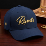 Rami's Palm premium performance baseball cap in navy blue, featuring the gold embroidered "Rami's" script logo on the front and a gold palm tree icon on the side panel.